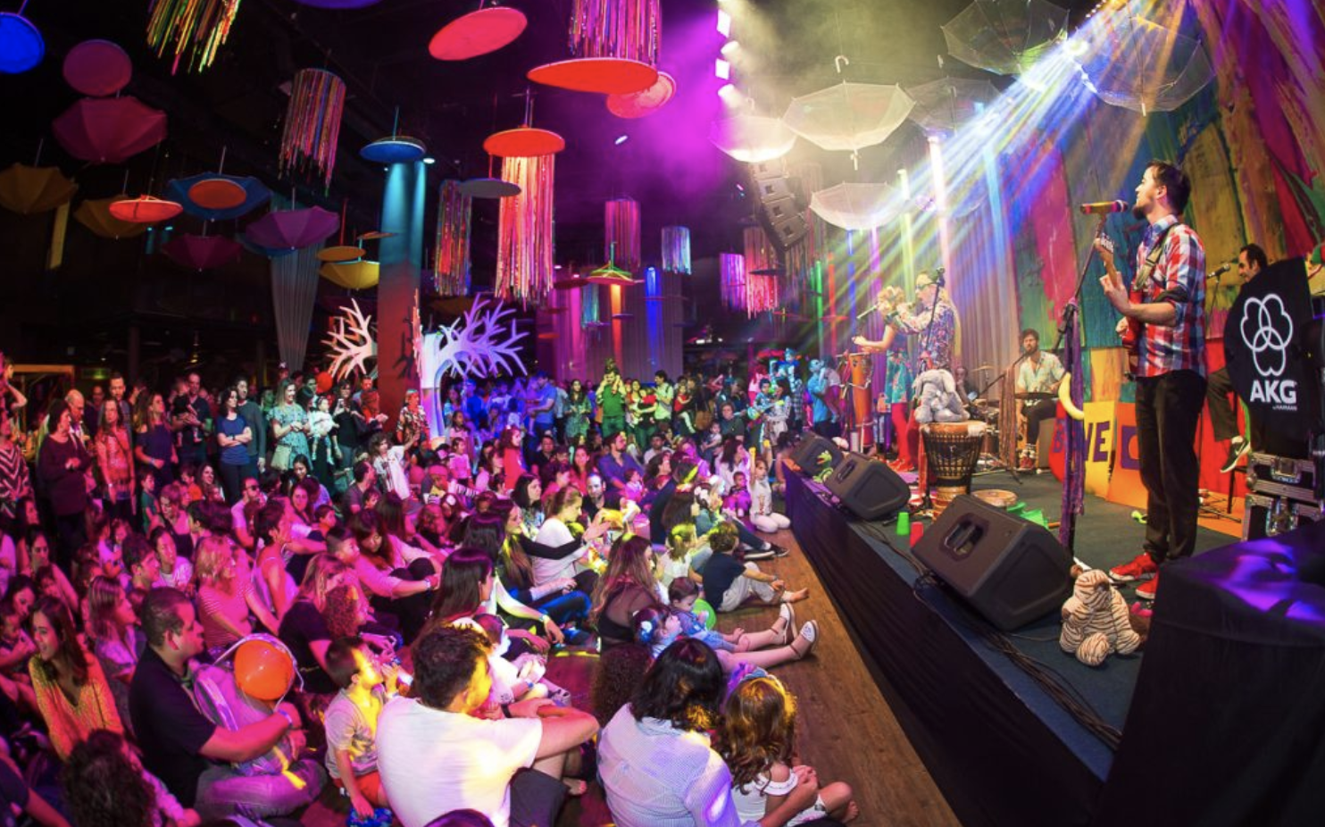 Uma multidão de pessoas está sentada em frente ao palco de um show.