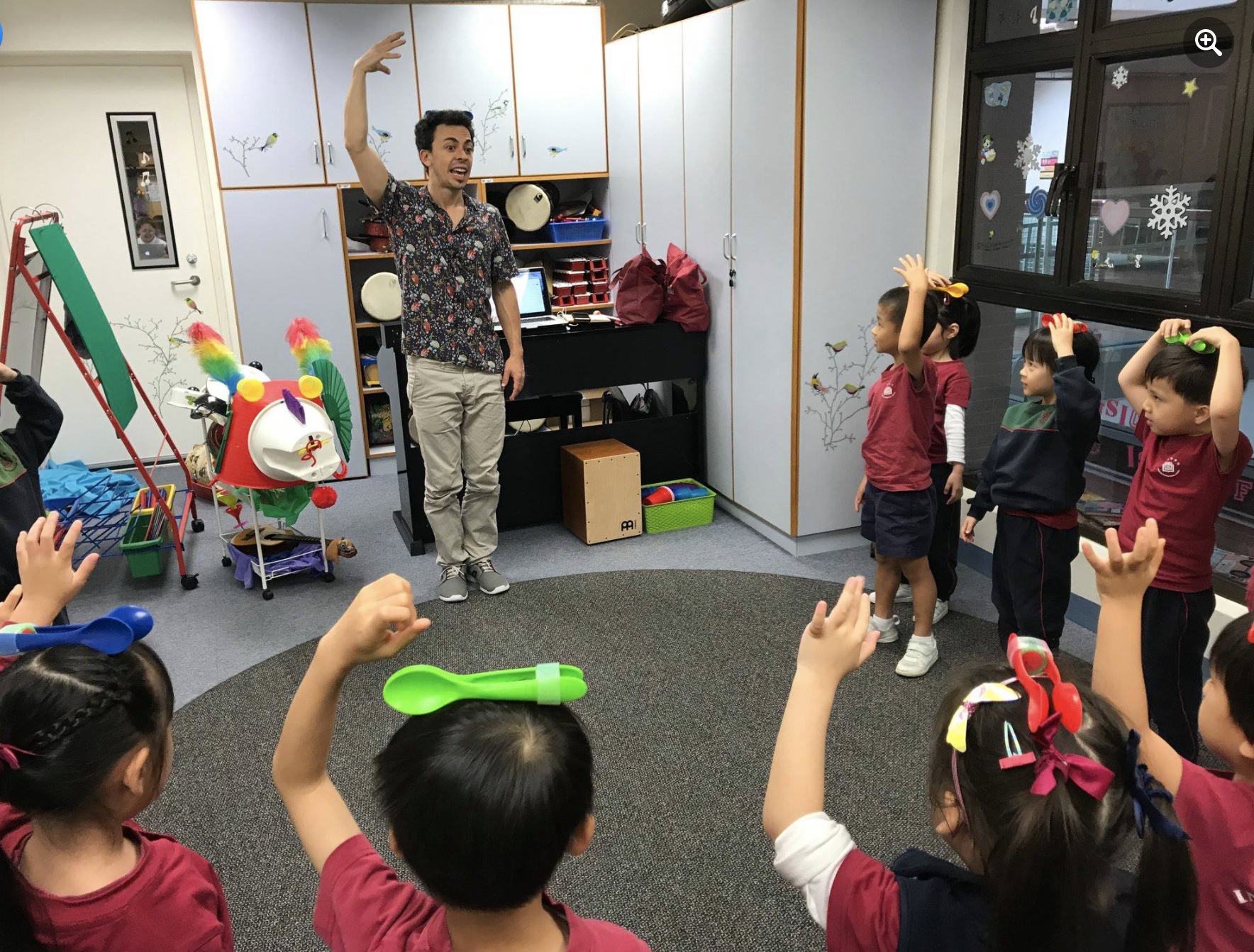 Um grupo de crianças forma um círculo com as mãos para cima.