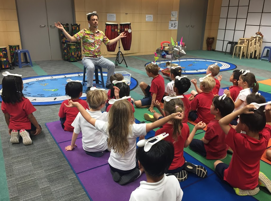 Um grupo de crianças está sentado em tapetes de ioga em uma sala.