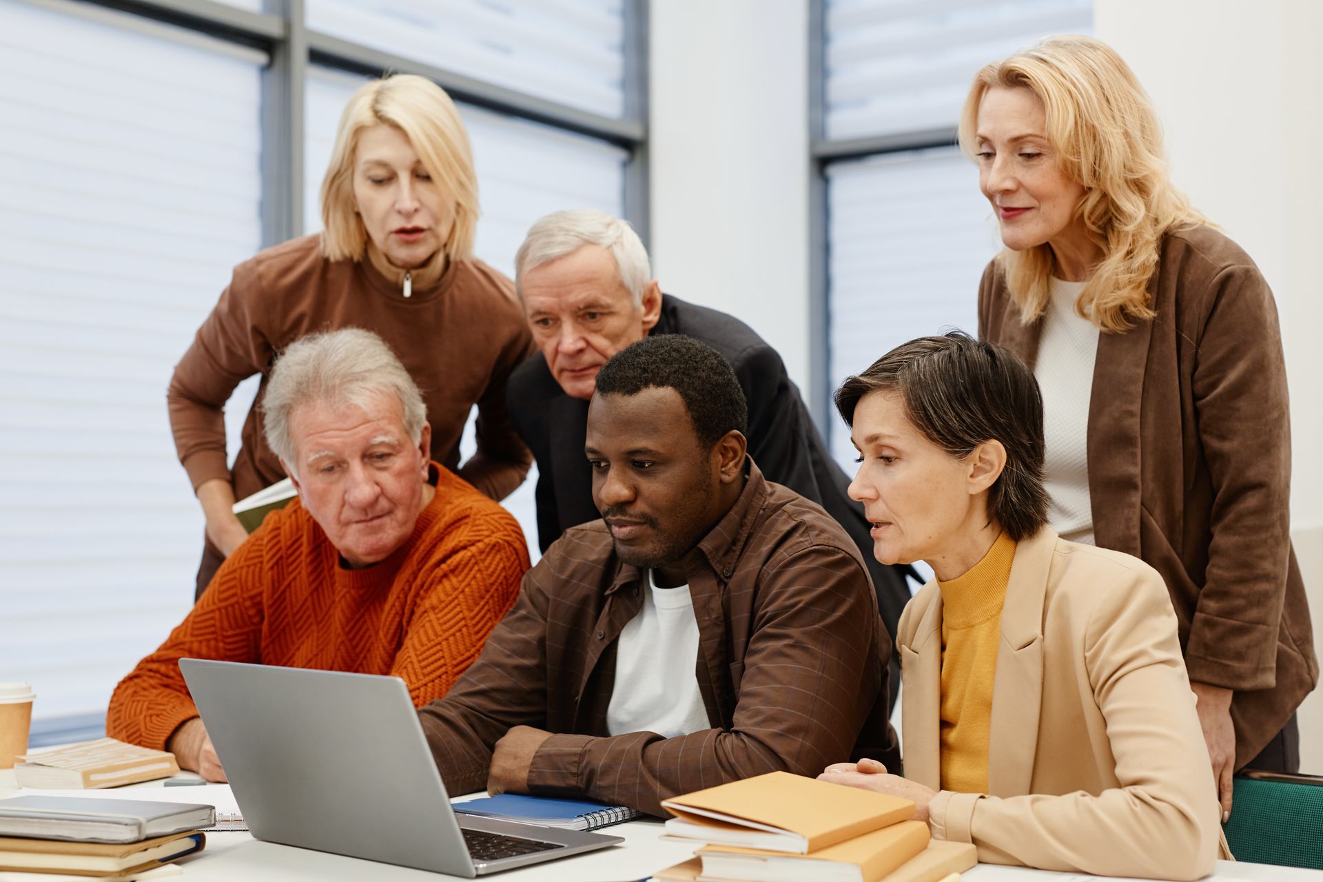 Grupo de pessoas em local de trabalho frente ao notebook
