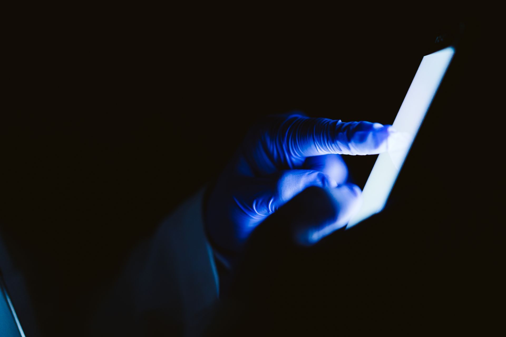 Mãos utilizando celular em local escuro