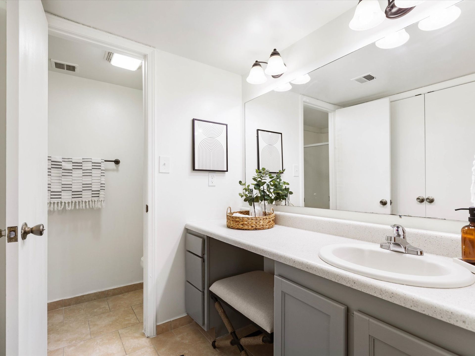 Bathroom with vanity, large mirror, and open doorway to a walk-in shower. Grey and white color scheme.