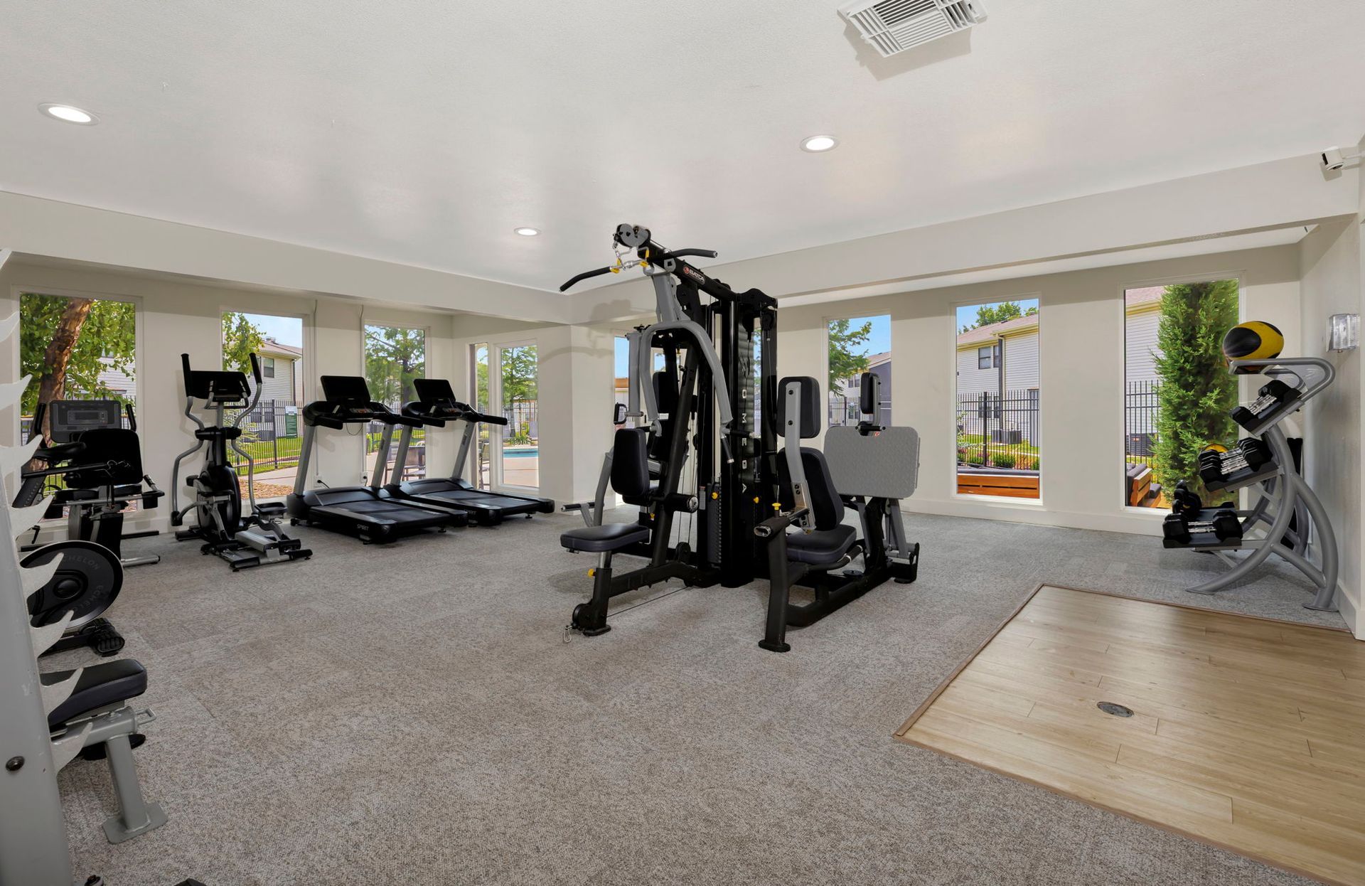 Gym with various exercise machines, including treadmills and weight equipment, with windows providing outdoor views.