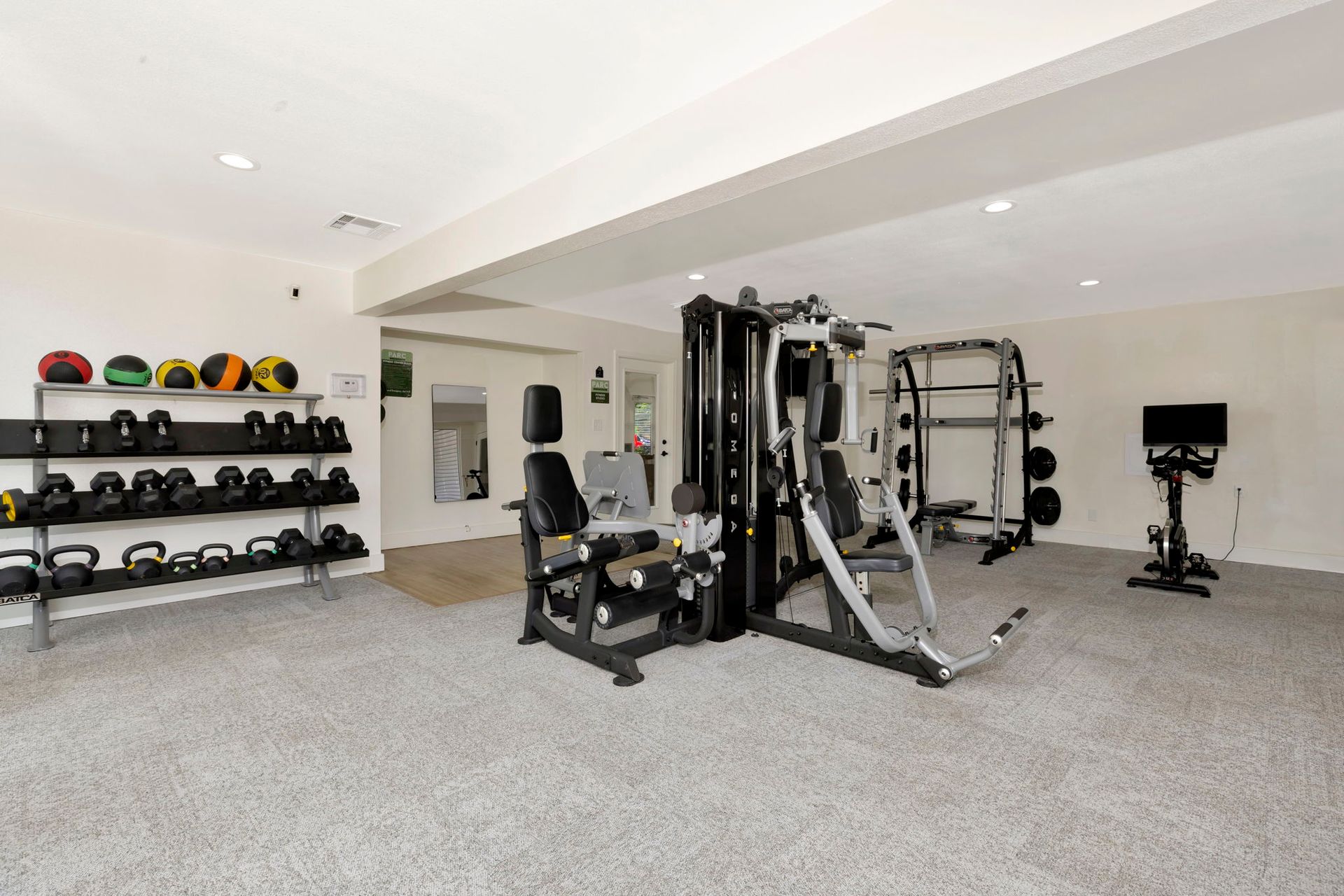 Home gym with various equipment: weights, machines, and a stationary bike.