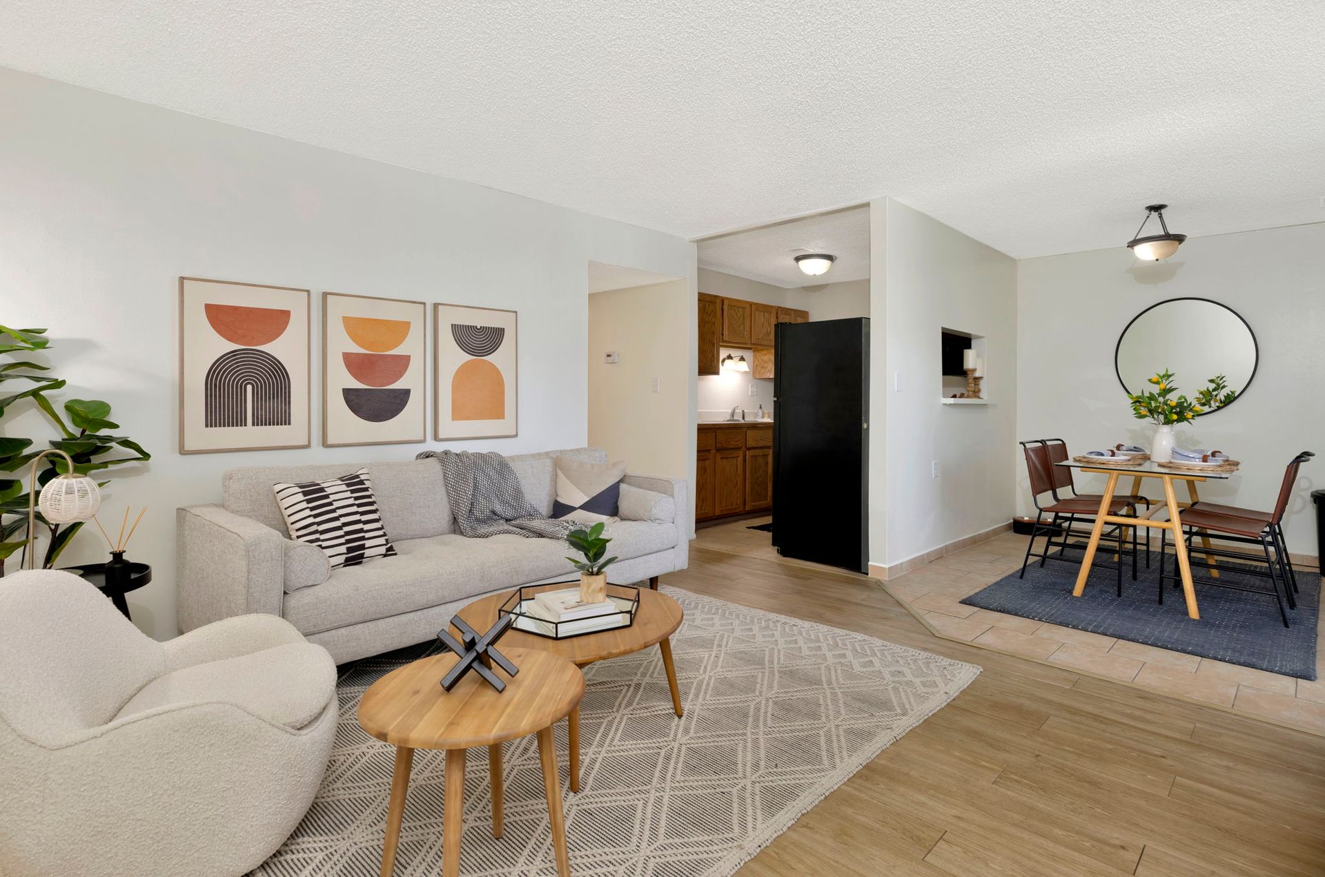 Living room with neutral furniture, artwork, and view into the kitchen and dining area.