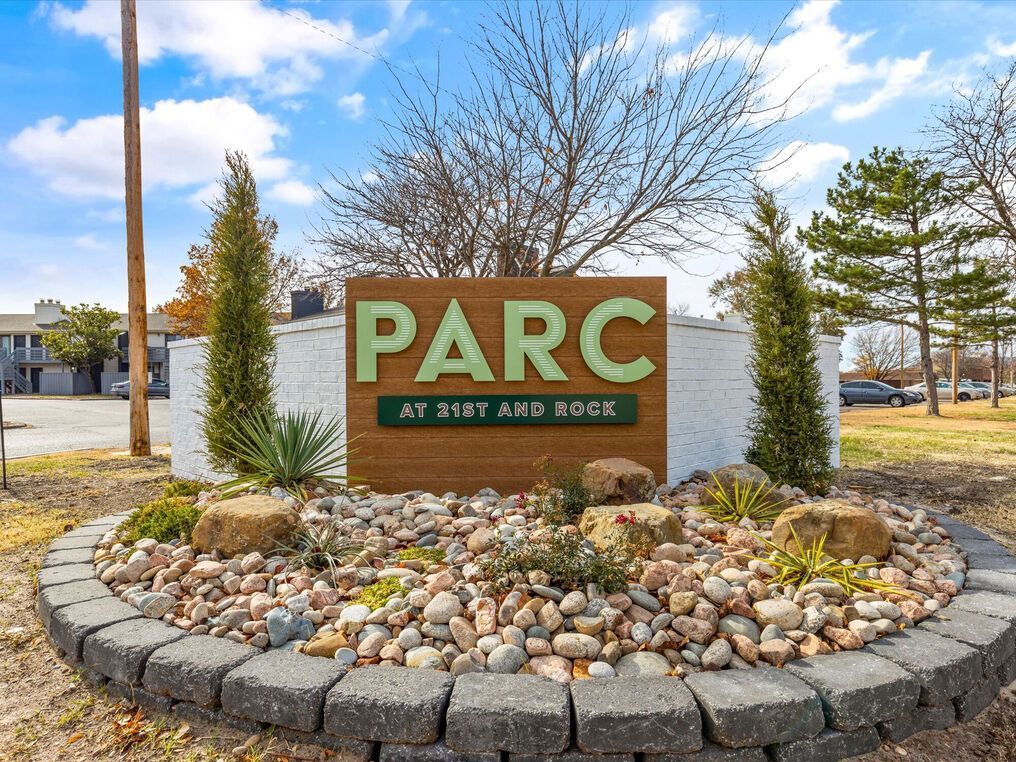 Sign for PARC at 31st and Rock. Green letters on a wooden background, surrounded by landscaping and a stone border.