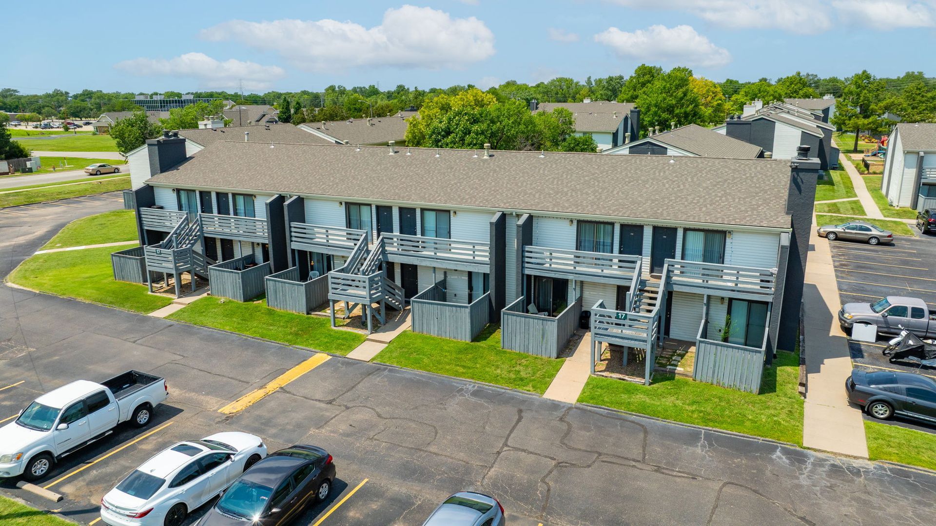 Townhouses with gray siding and brown roofs, in a parking lot.