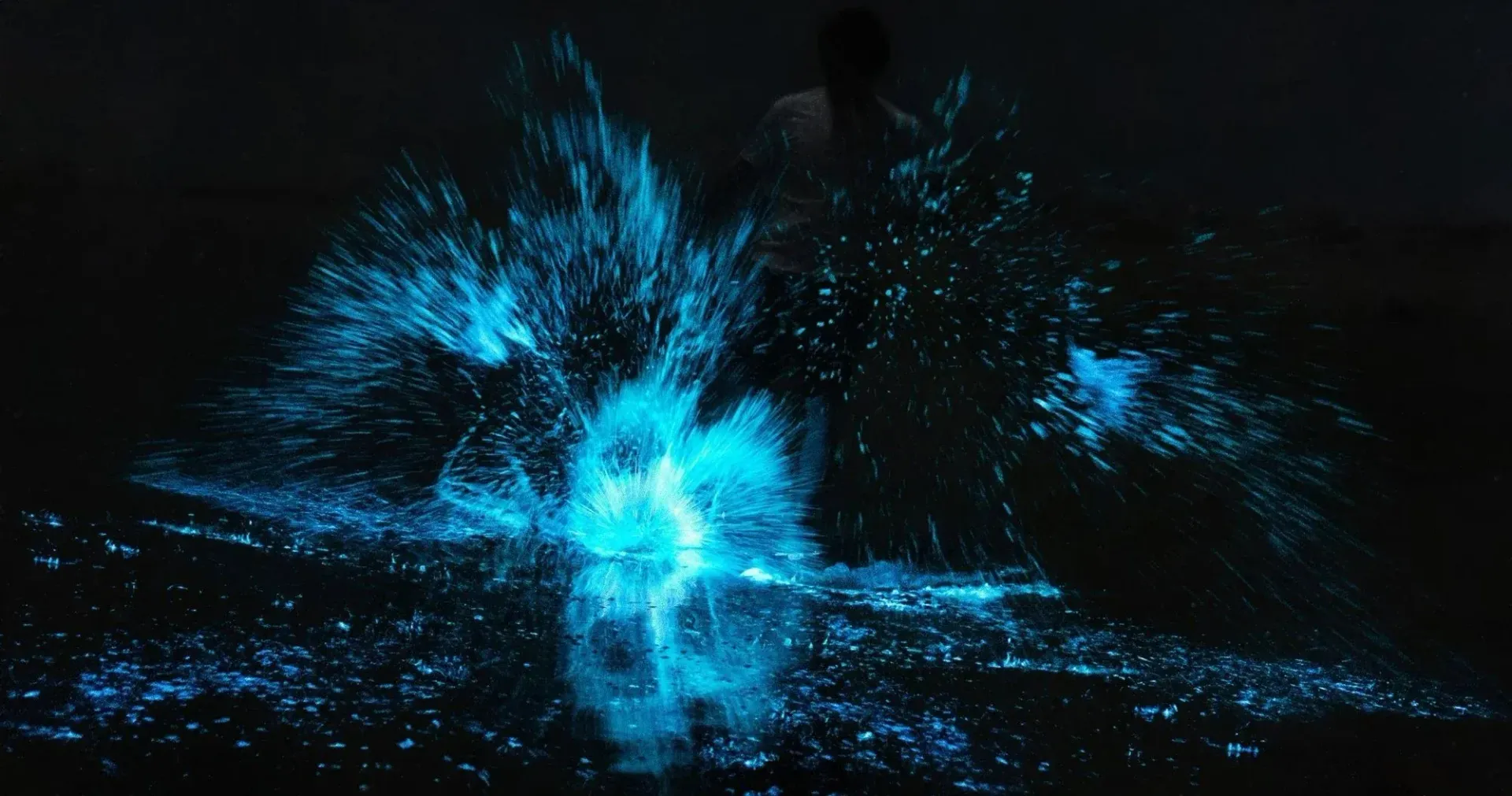 Blue glowing particle burst in a dark abstract scene