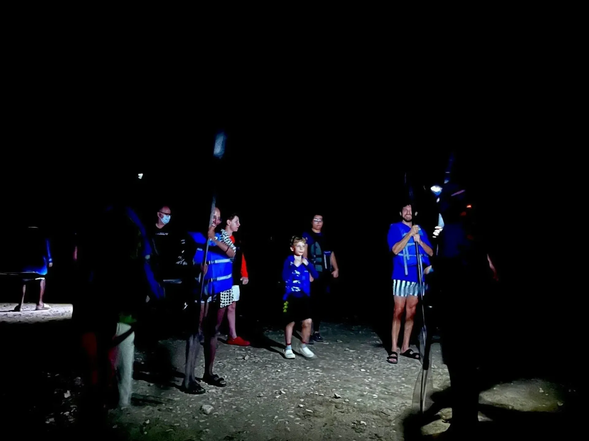 Group of people standing outdoors at night, lit by flashlights, with one person raising a flag.