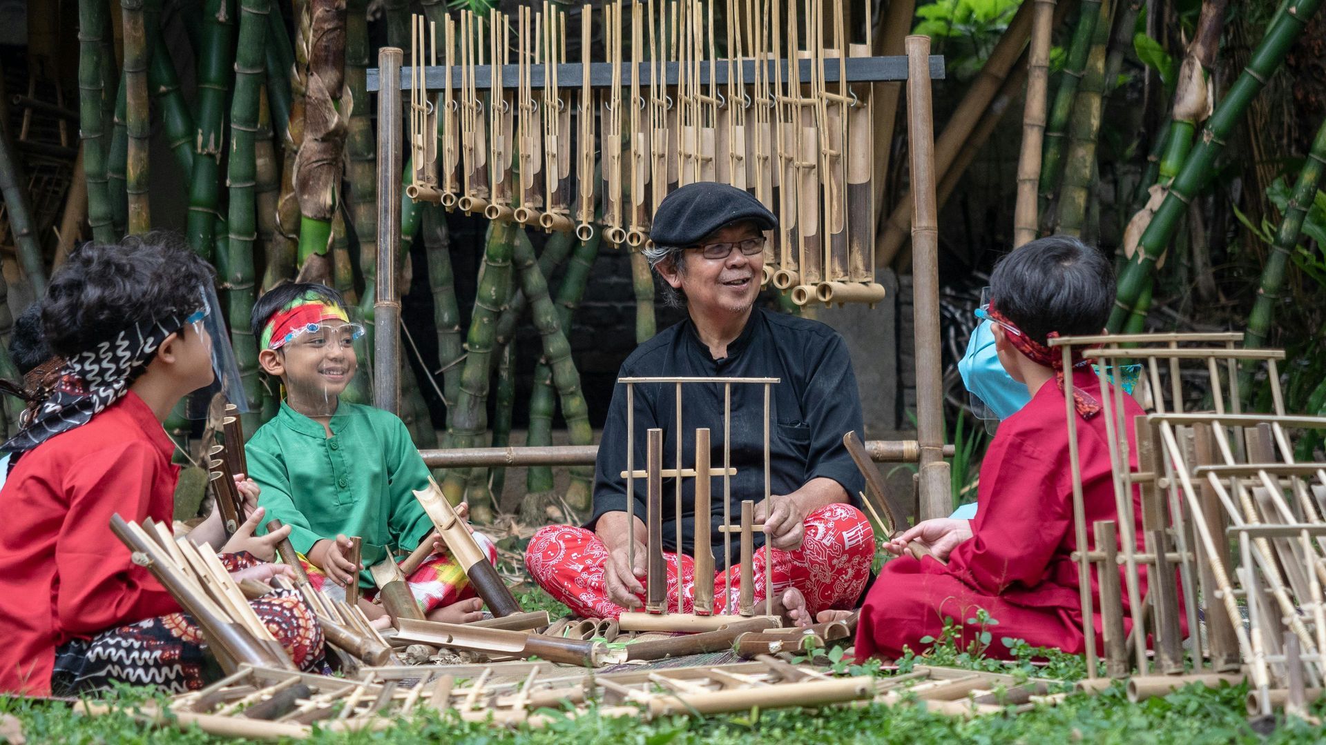 People weaving bamboo baskets outdoors, seated around a bamboo work area in a rustic setting.