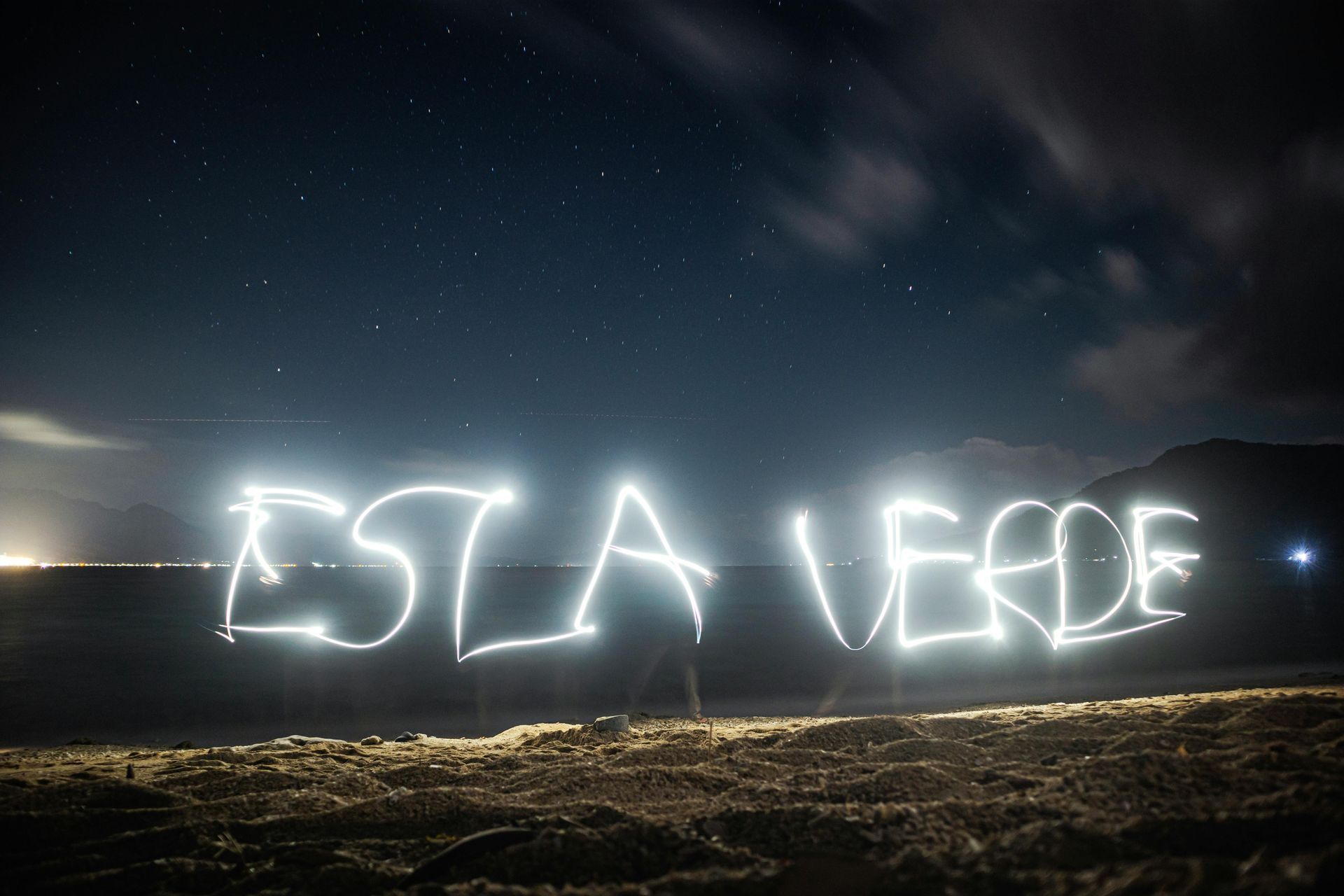 Night landscape with bright light writing across the sky above a dark field