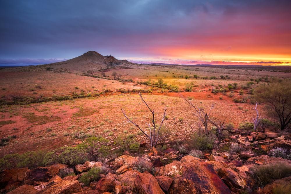 A Sunset Over A Desert Landscape With A Mountain In The Background — LJ's Technical Services In Northern Territory, AU