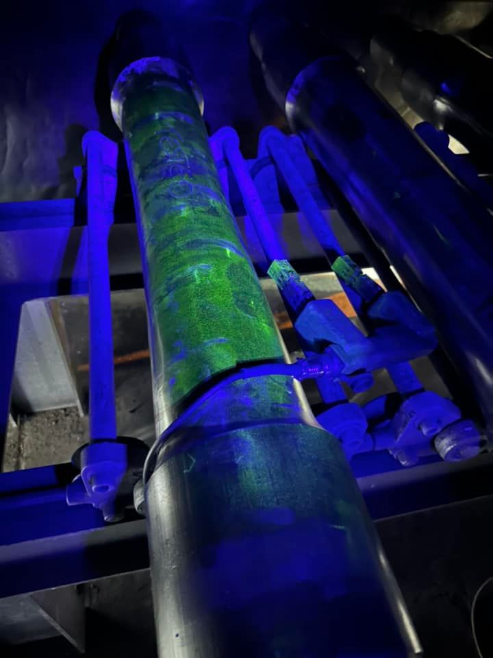 A Green Pipe Is Glowing In The Dark Under A Blue Light — LJ's Technical Services In Burdell, QLD