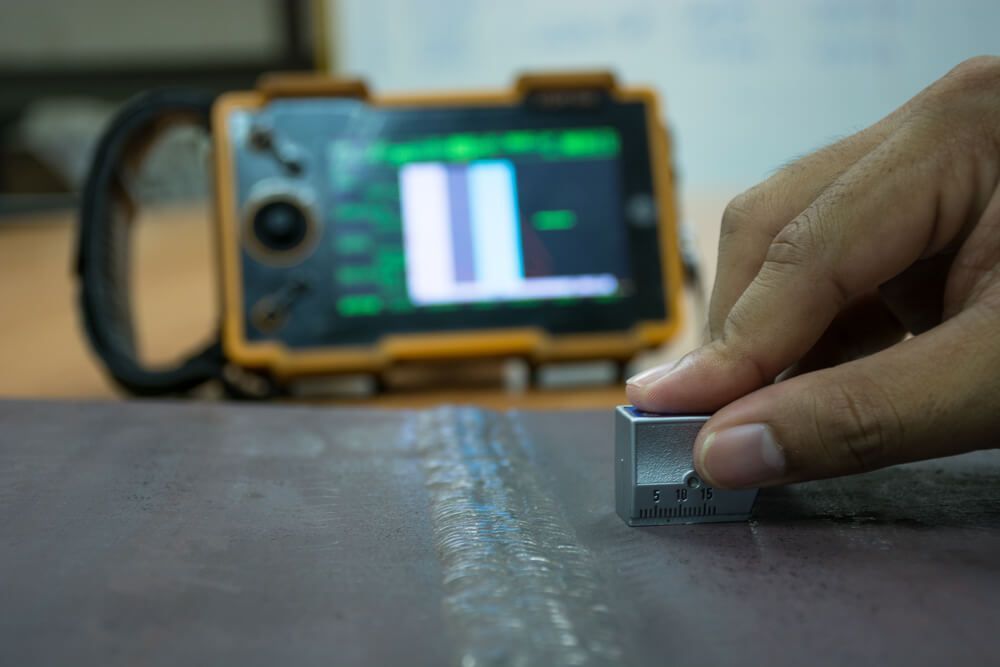 A person is using a metal detector to check the thickness of a piece of metal — LJ's Technical Services In South Australia, AU