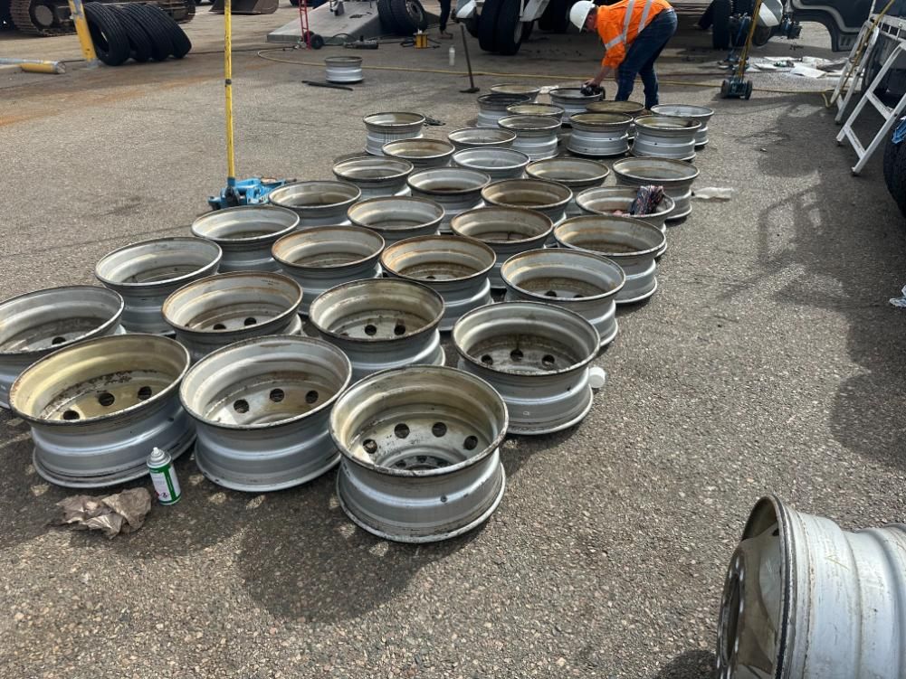 A Man Is Working On A Pile Of Wheels In A Parking Lot — LJ's Technical Services In Burdell, QLD