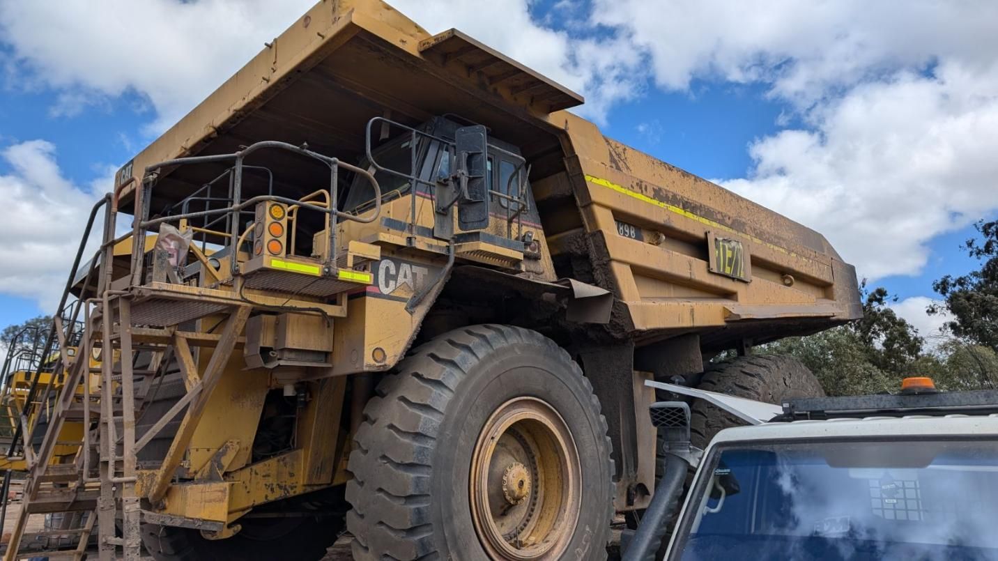 A Large Dump Truck Is Parked Next To A Car On A Dirt Road — LJ's Technical Services In Burdell, QLD
