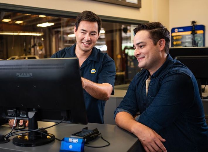 Man in NAPA uniform helping customer on computer monitor  | China Spring Lube & Service
