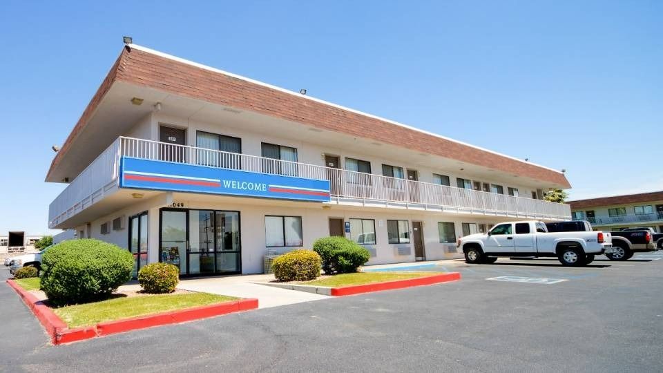 Two-story motel with a white truck parked out front on a sunny day.