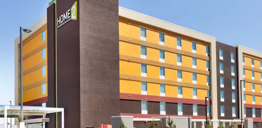 Home2 Suites by Hilton hotel building. Orange, brown, and tan exterior with blue sky.