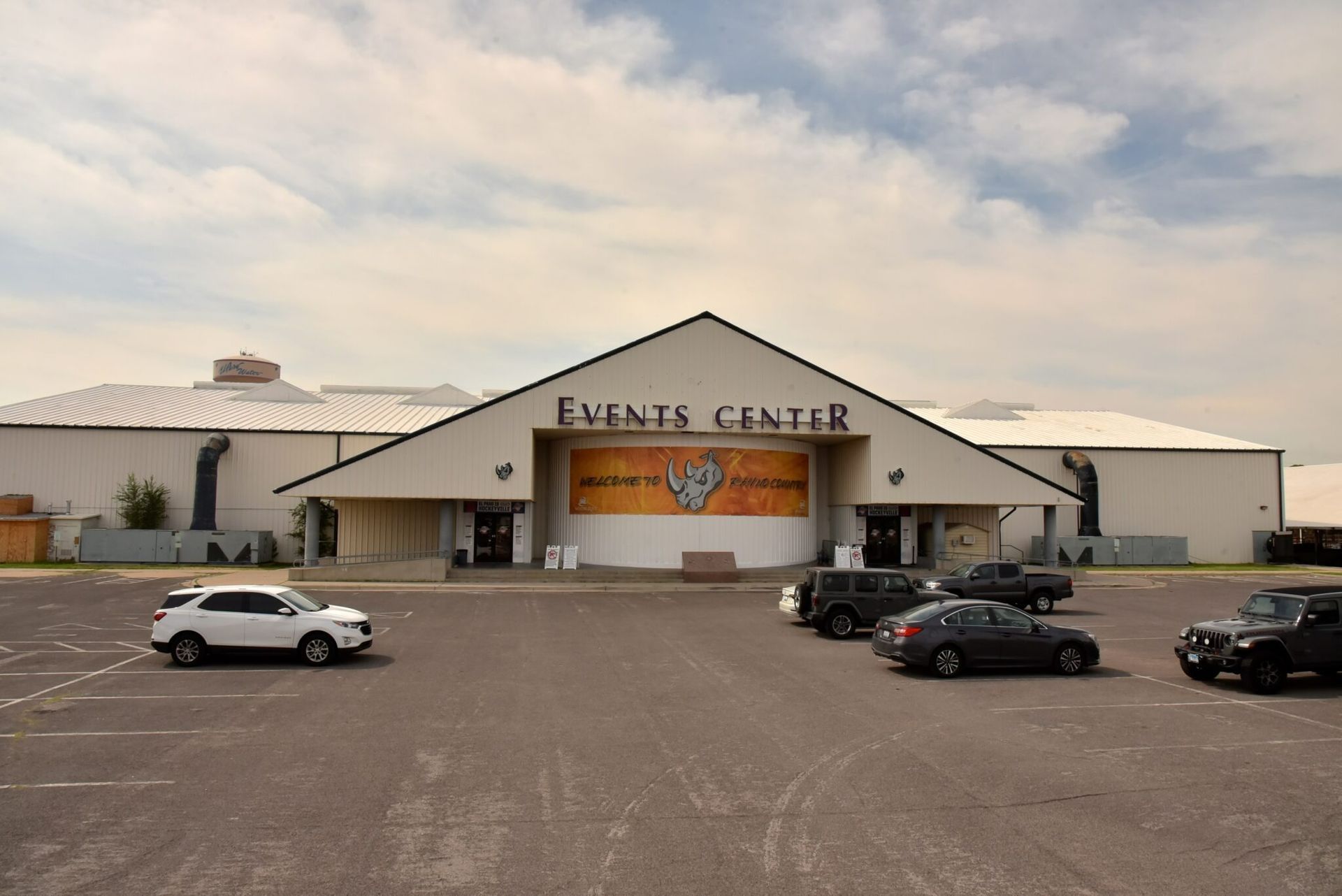 Events Center exterior with cars parked, under a cloudy sky.