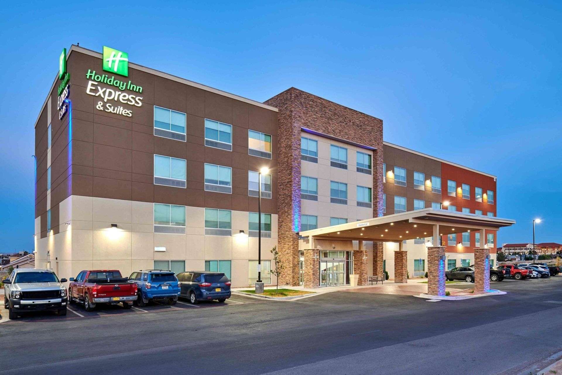 Holiday Inn Express & Suites hotel at dusk, with cars parked out front.