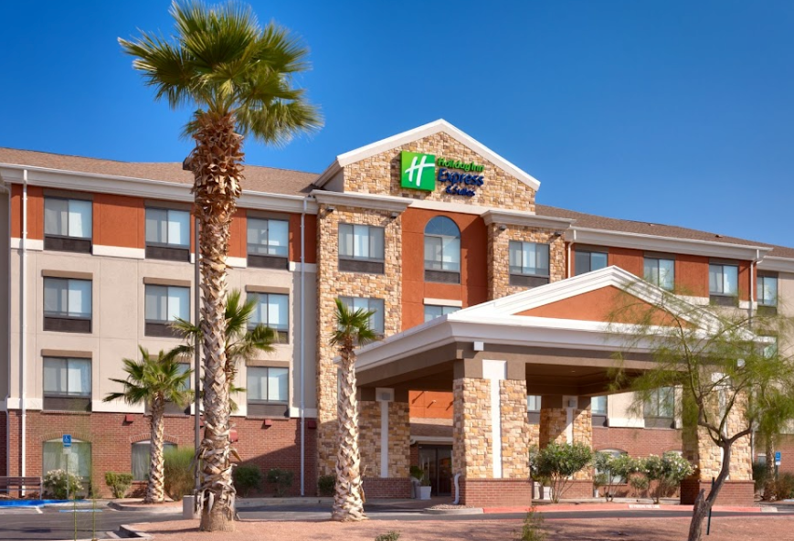 Holiday Inn Express exterior with palm trees, brick, stone, and blue sky.