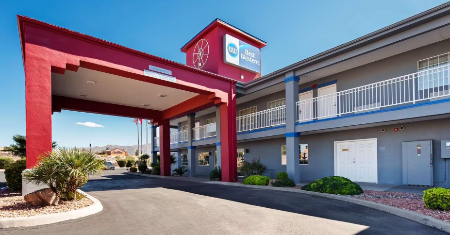 Best Western hotel exterior with a red entrance, gray walls, and blue sky.
