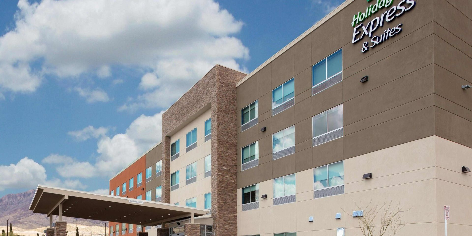 Holiday Inn Express and Suites hotel exterior under a blue sky with clouds.