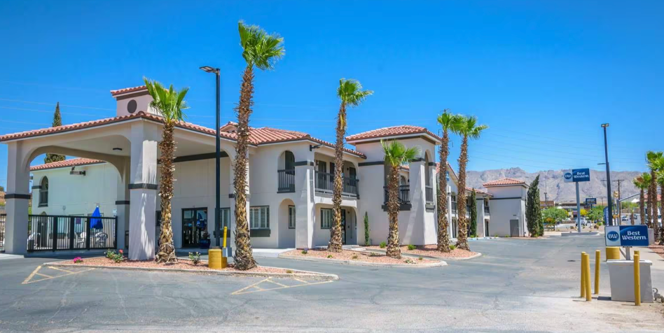 A Best Western hotel in a desert setting with palm trees under a bright blue sky.