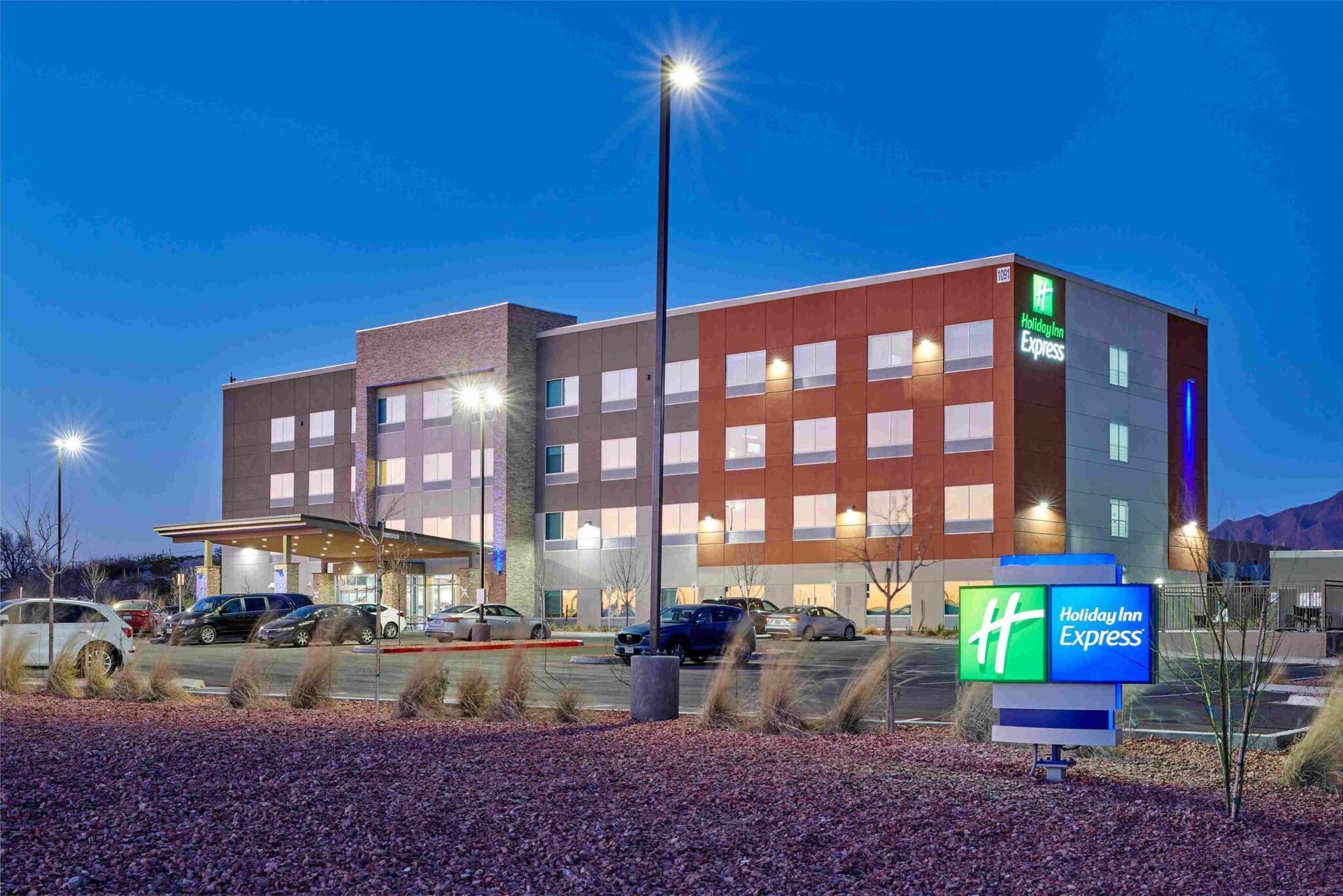 Holiday Inn Express hotel at dusk with lit sign and cars.