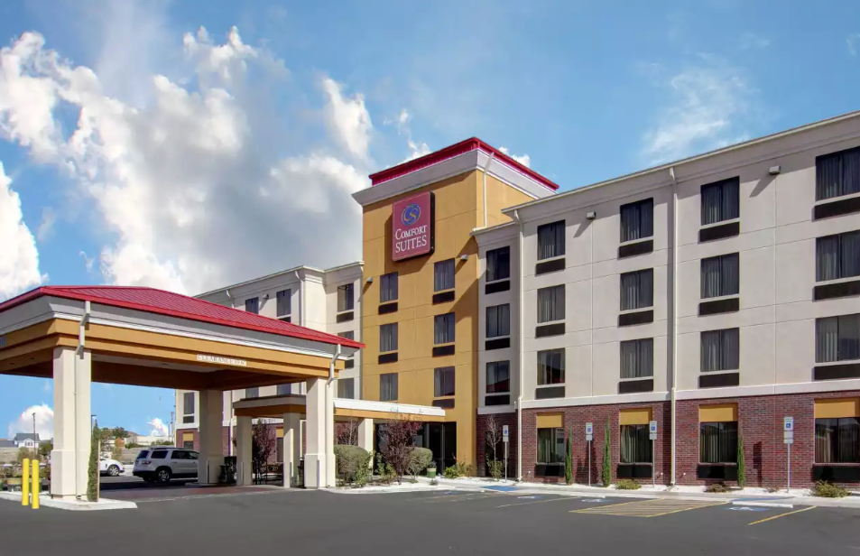 Sleep Inn hotel exterior on a sunny day; beige building, red accents, blue sky.