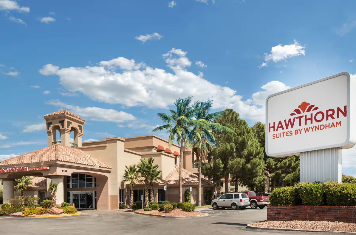Hawthorn Suites by Wyndham hotel exterior; beige building with sign, palm trees, and blue sky.