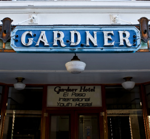 Sign for Gardner Hotel in El Paso, Texas; blue sign with white lettering; arched entry.