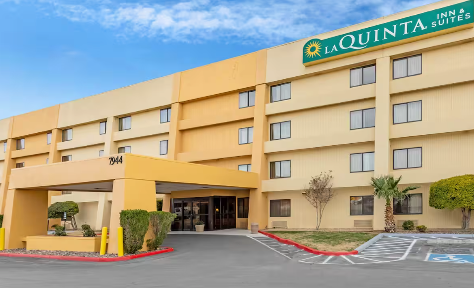 La Quinta Inn & Suites hotel exterior with yellow facade, entrance canopy, and parking area.