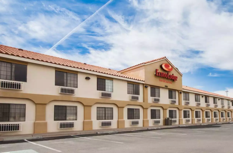 Exterior view of a two-story, beige and tan hotel with a sign for 