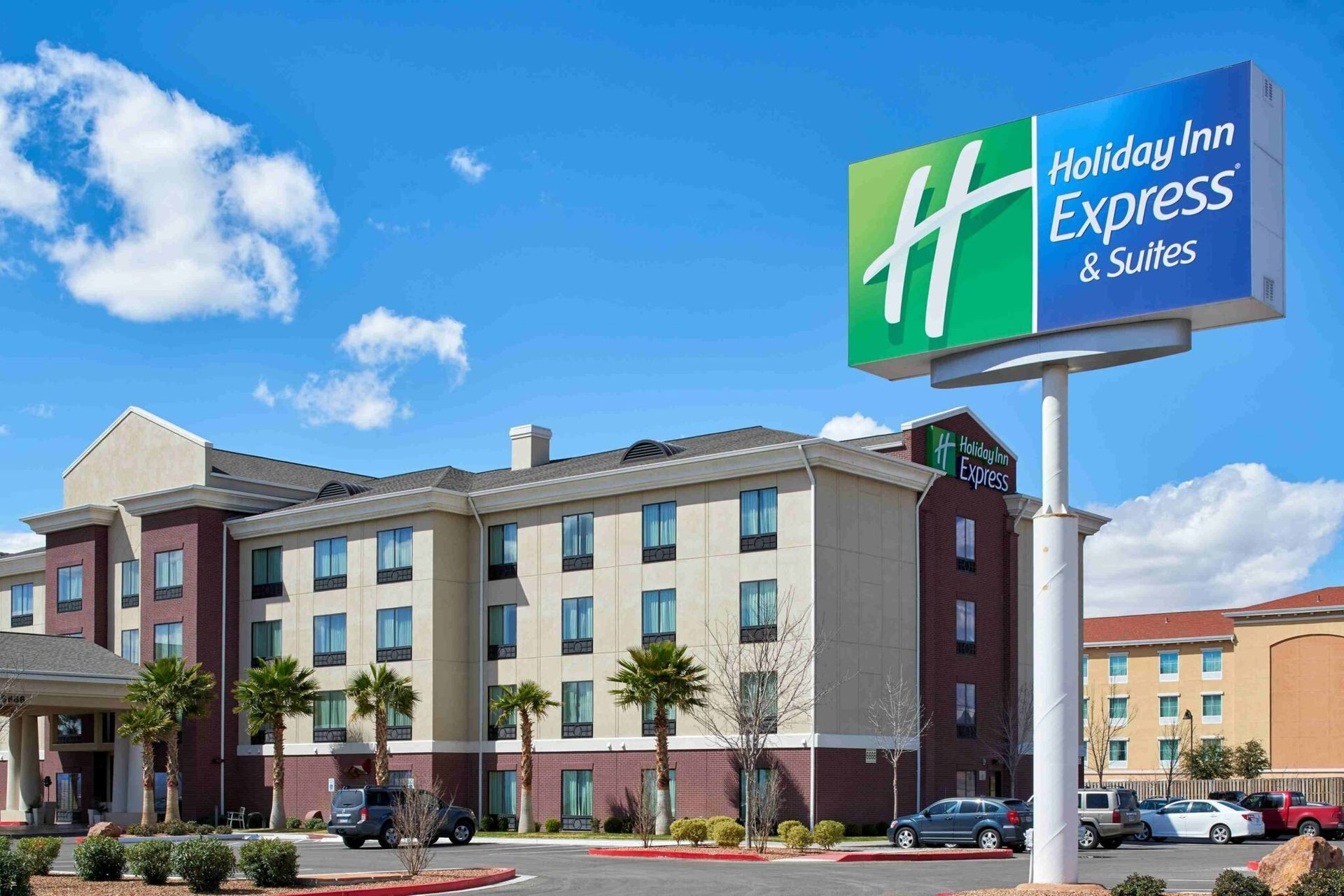Holiday Inn Express & Suites hotel exterior with sign in blue sky.