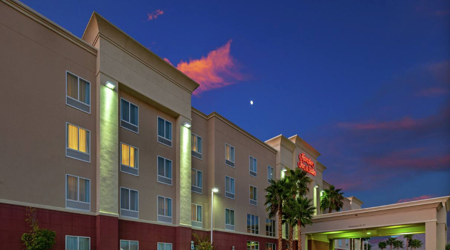 Hotel exterior at dusk with a colorful sky, lit windows, and a covered entrance.