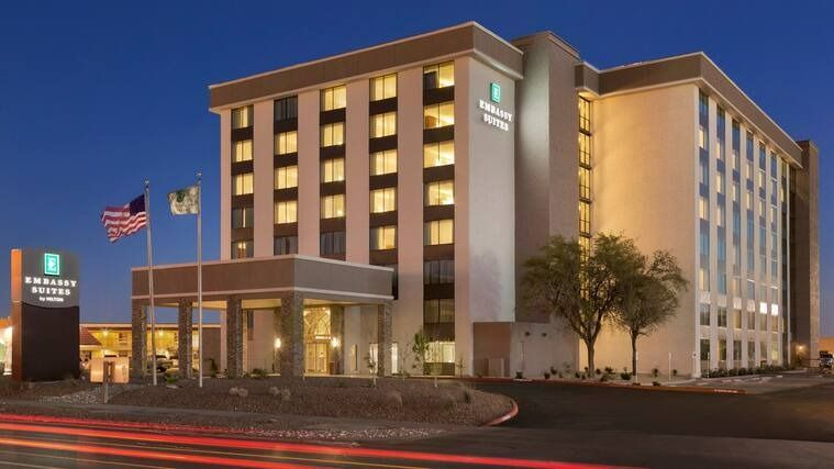 Embassy Suites hotel exterior at dusk, with flags and entry canopy.