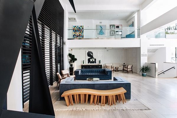 Modern, open-concept lobby with blue sofa, wooden bench, and two-story design. White walls, artwork, and natural light.