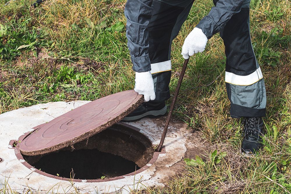 A man is opening a manhole cover with a stick.