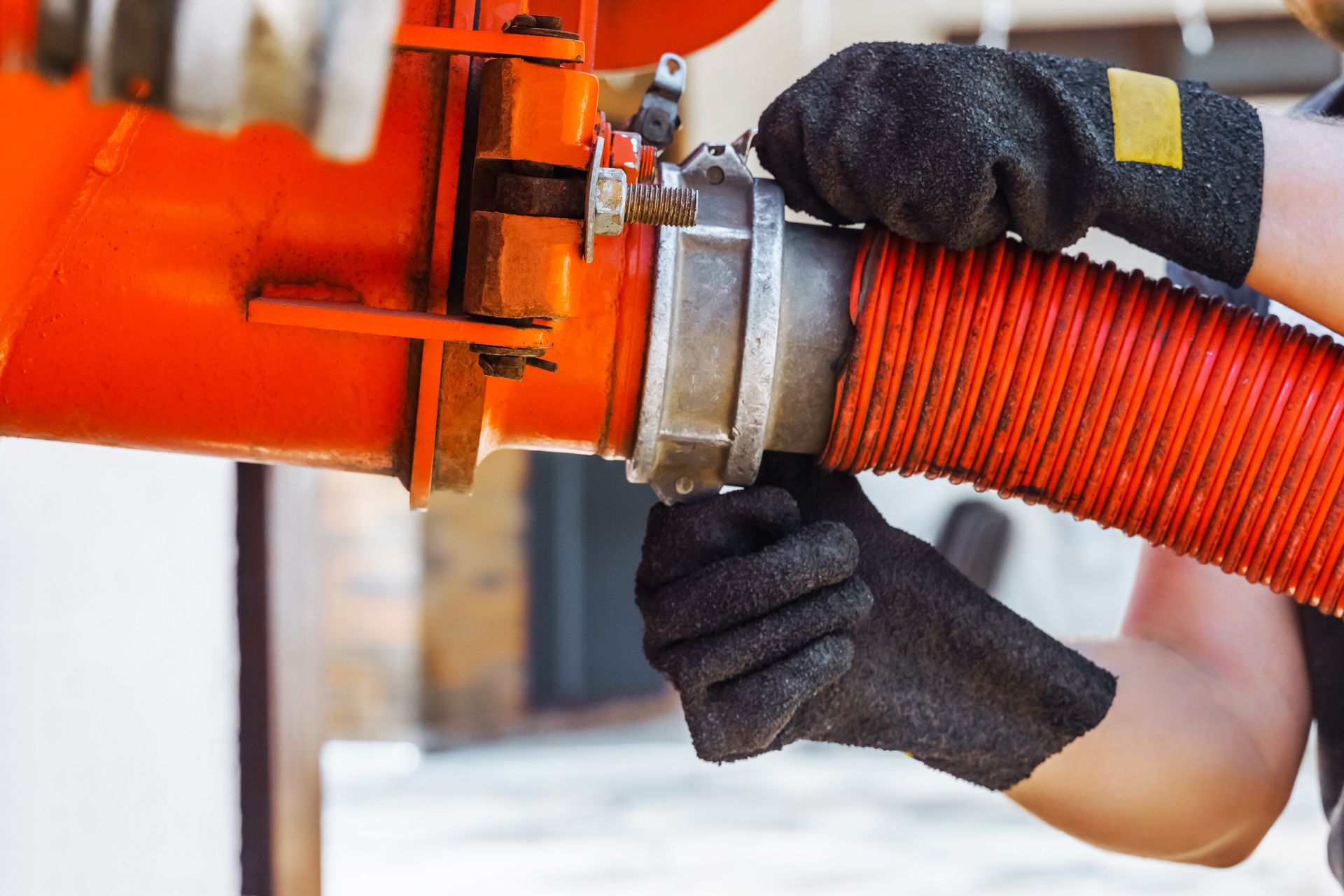 Septic pumping worker’s hand connects a suction hose to a sewage tanker truck.