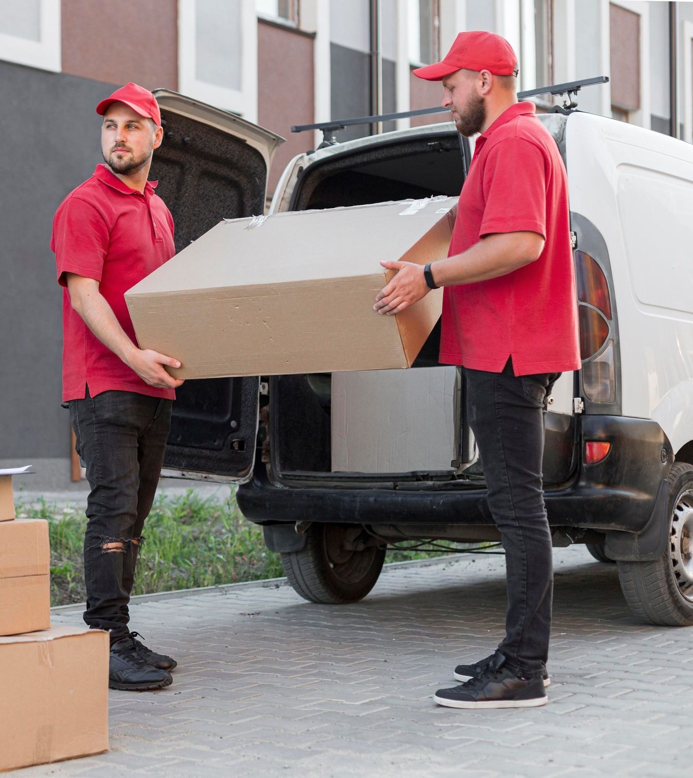 two delivery men are standing next to a van holding boxes .