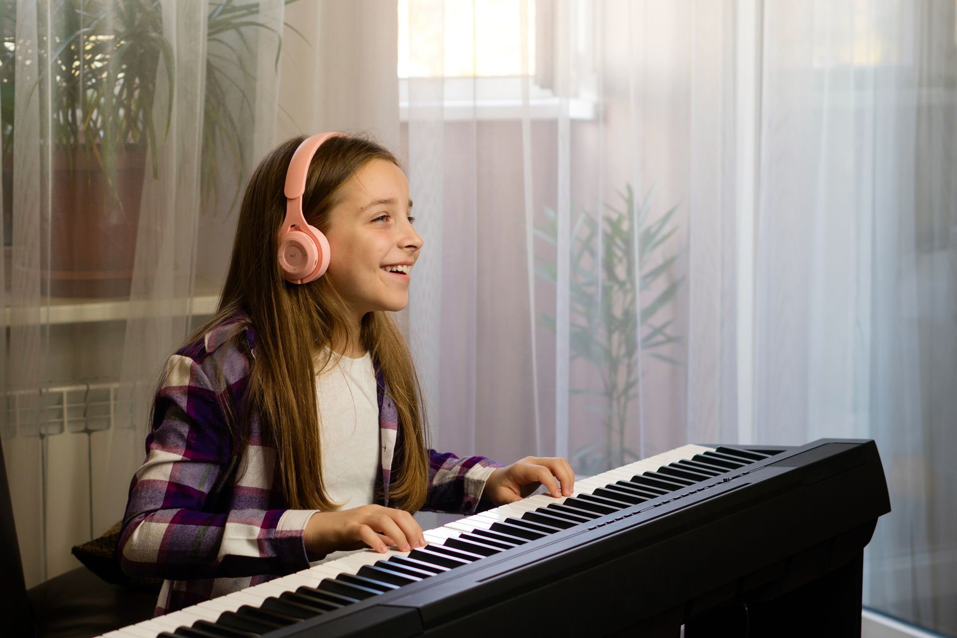 a young girl wearing headphones is playing a piano .