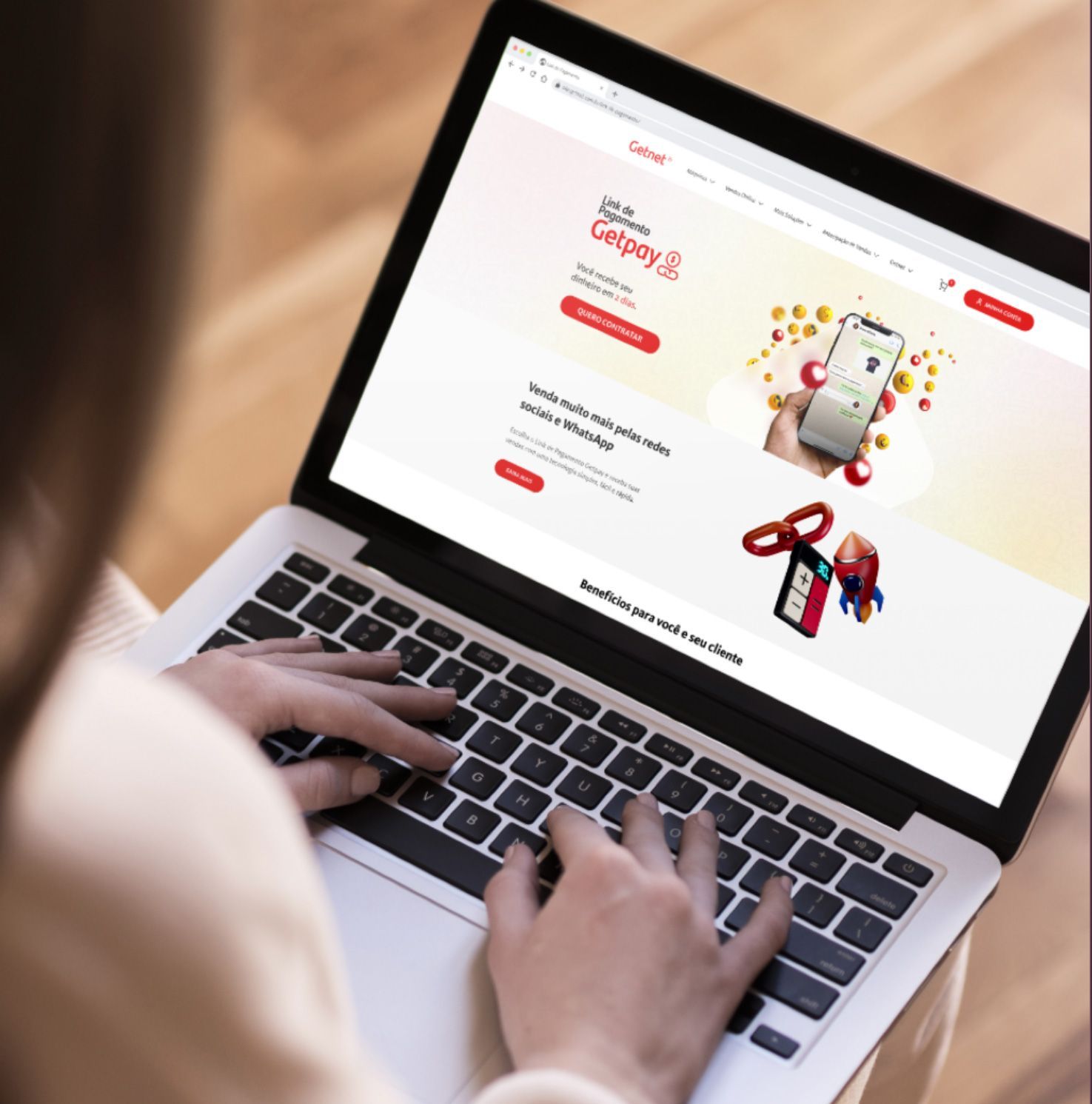 Uma pessoa está digitando em um laptop com um telefone na tela