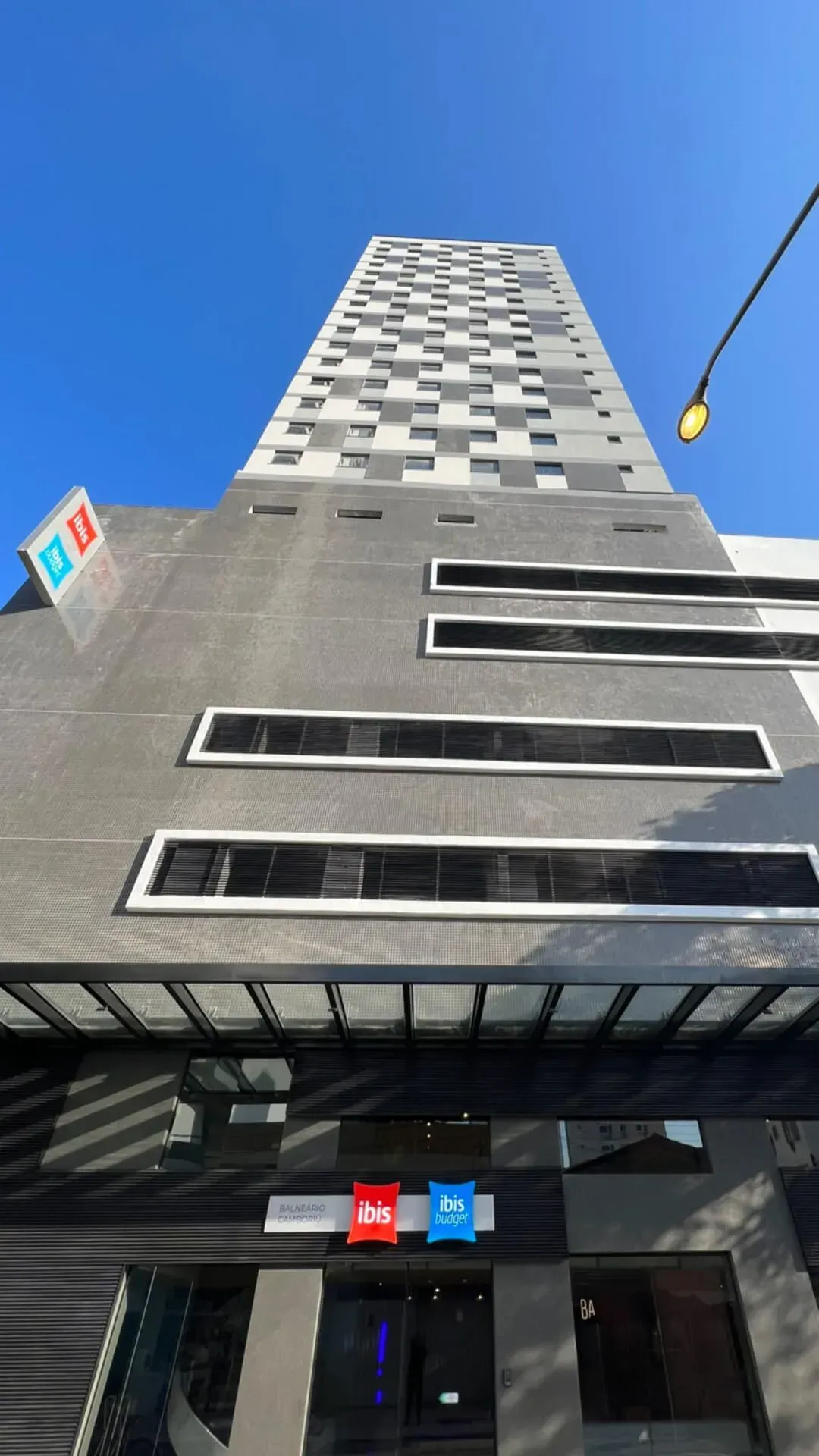 Olhando para um prédio alto com um céu azul ao fundo.