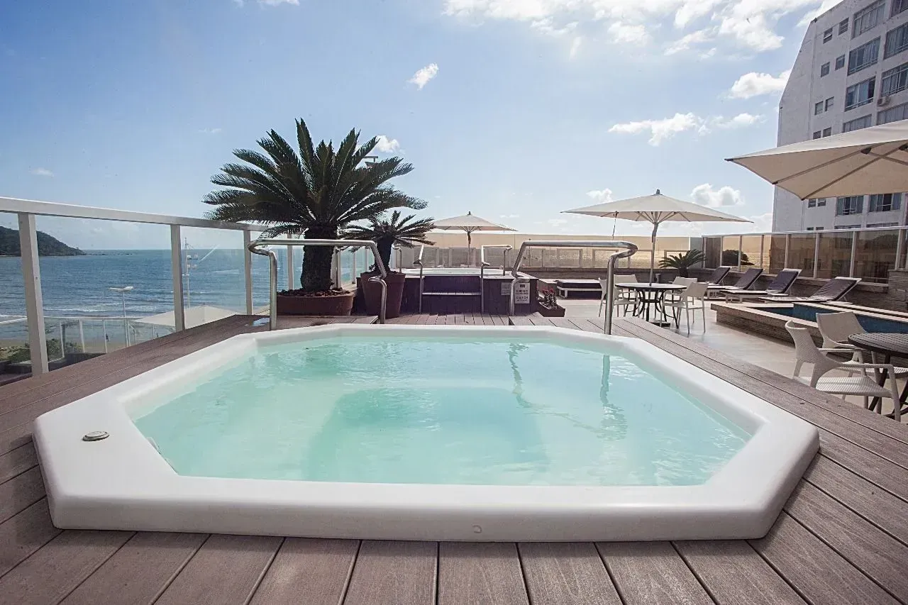 Uma grande piscina em um deck com vista para o oceano.