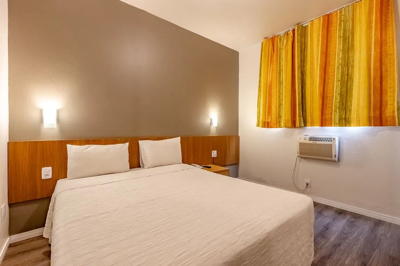 Um quarto de hotel com uma cama king size e cortinas listradas.