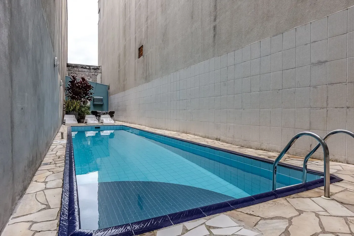 Uma grande piscina é cercada por um muro de pedra e cadeiras.