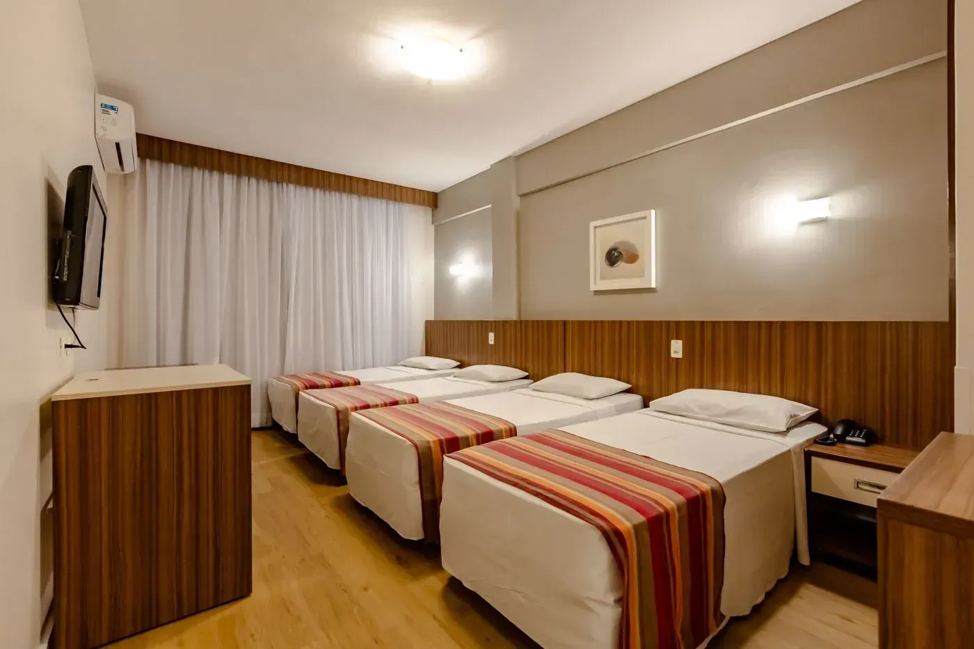 Um quarto de hotel com quatro camas e uma televisão.