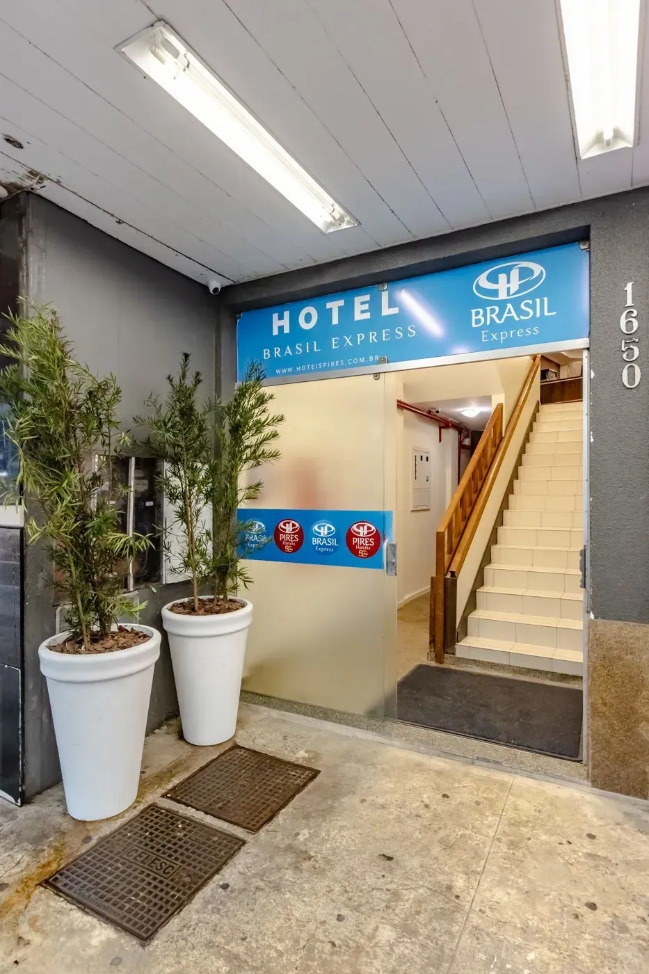 Um hotel com escadas e vasos de plantas na frente.